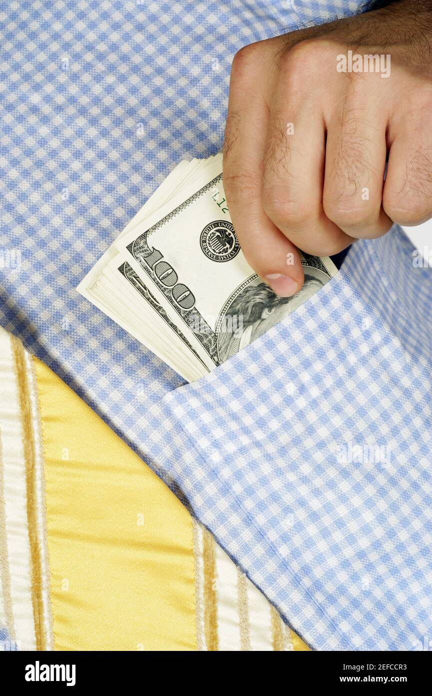 Vista in sezione intermedia di un uomo d'affari che mette i soldi nel suo tasca per camicia Foto Stock