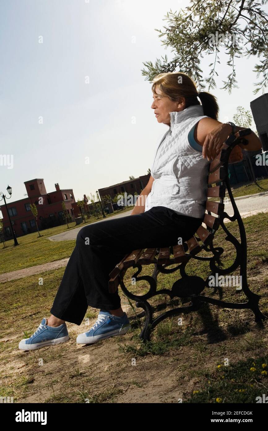 Profilo laterale di una donna anziana che riposa su una panca Foto Stock