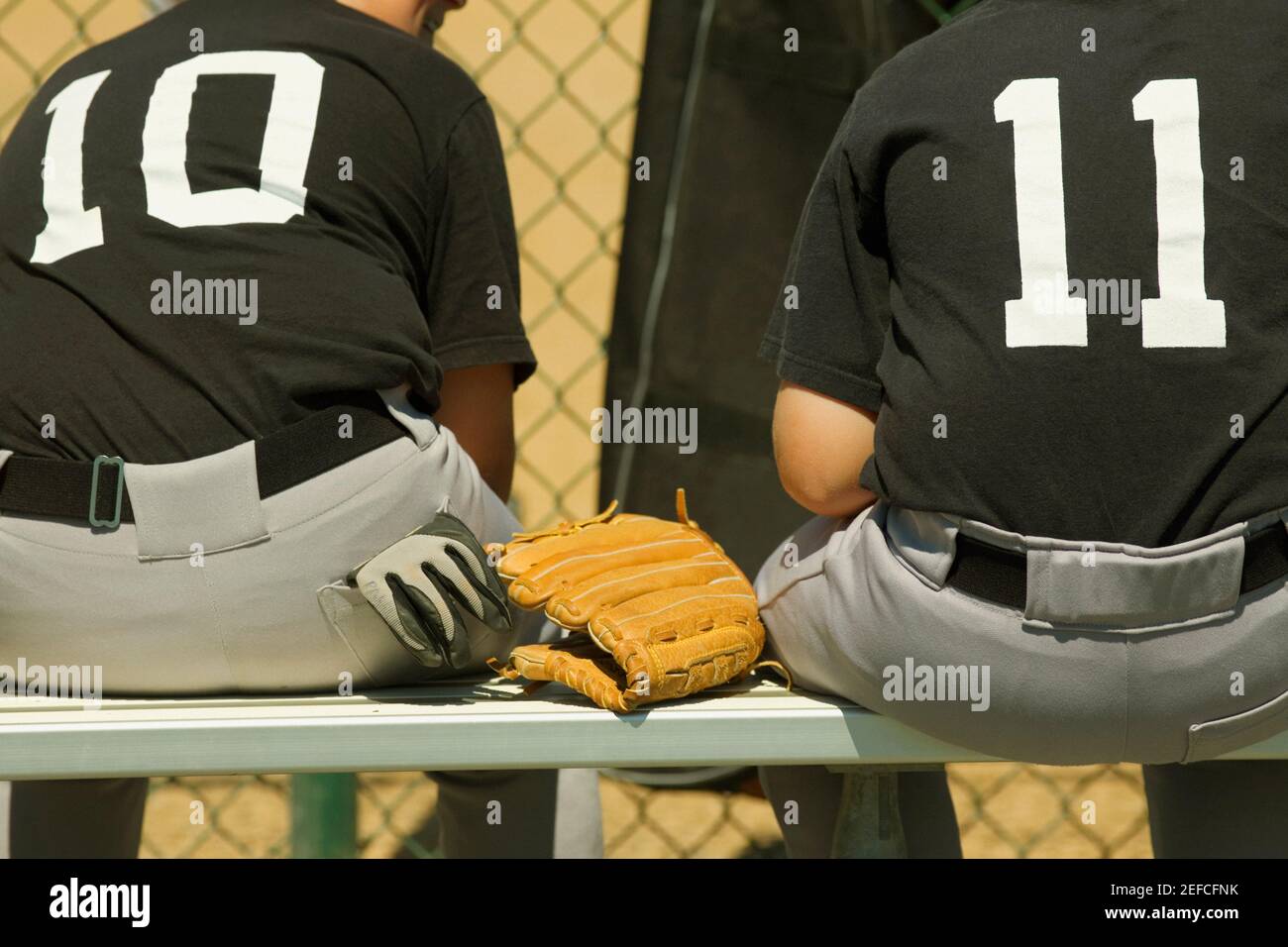 Vista posteriore di due giocatori di baseball seduti su una panchina Foto Stock