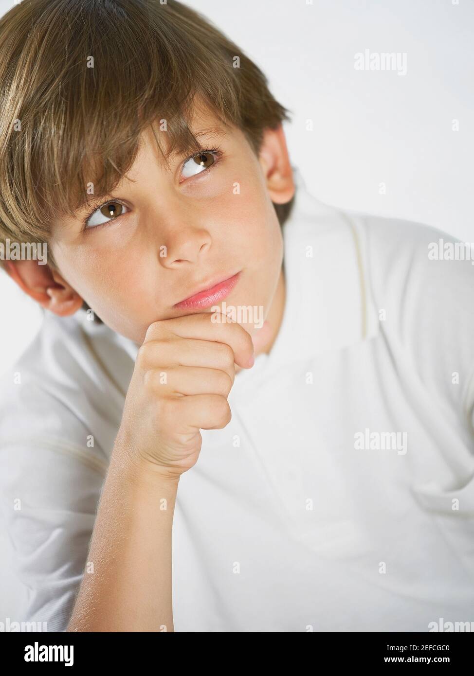 Primo piano di un ragazzo che pensa con la mano su di lui mento Foto Stock