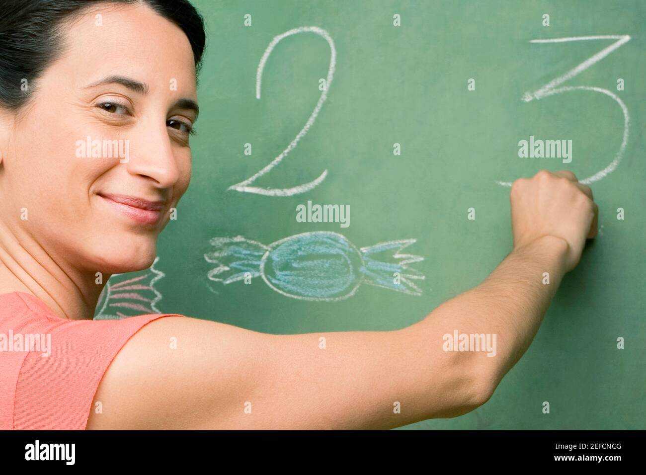 Ritratto di una insegnante di sesso femminile che scrive su una bacheca Foto Stock