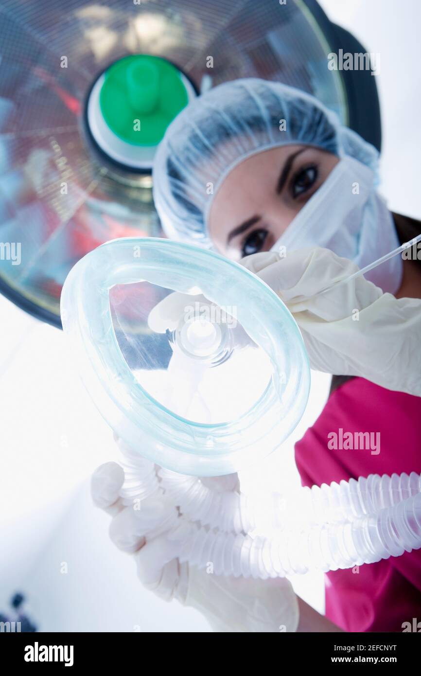 Basso angolo di visione di un chirurgo femmina tenendo una maschera ad ossigeno Foto Stock