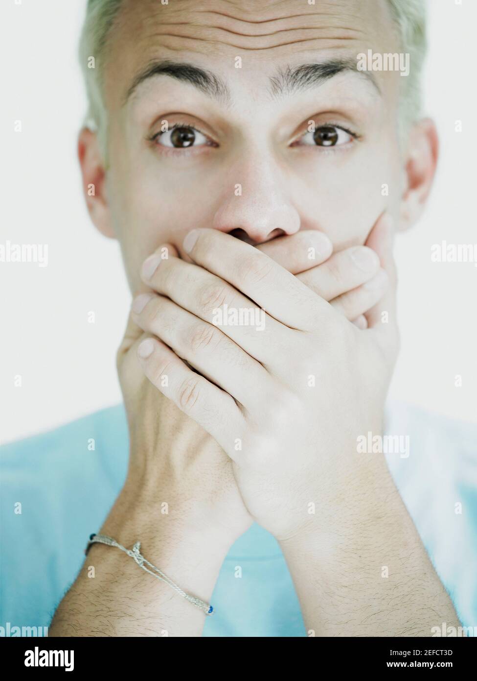 Ritratto di un giovane uomo che copre la bocca con le mani Foto Stock