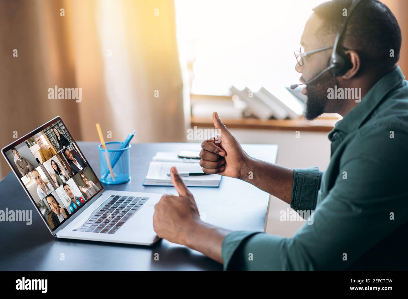 L'uomo afro-americano di successo utilizza un'applicazione per la comunicazione video online con i colleghi utilizzando un laptop, meeting online tramite videoconferenza. Brainstorming di gruppo, webinar, lezione online Foto Stock