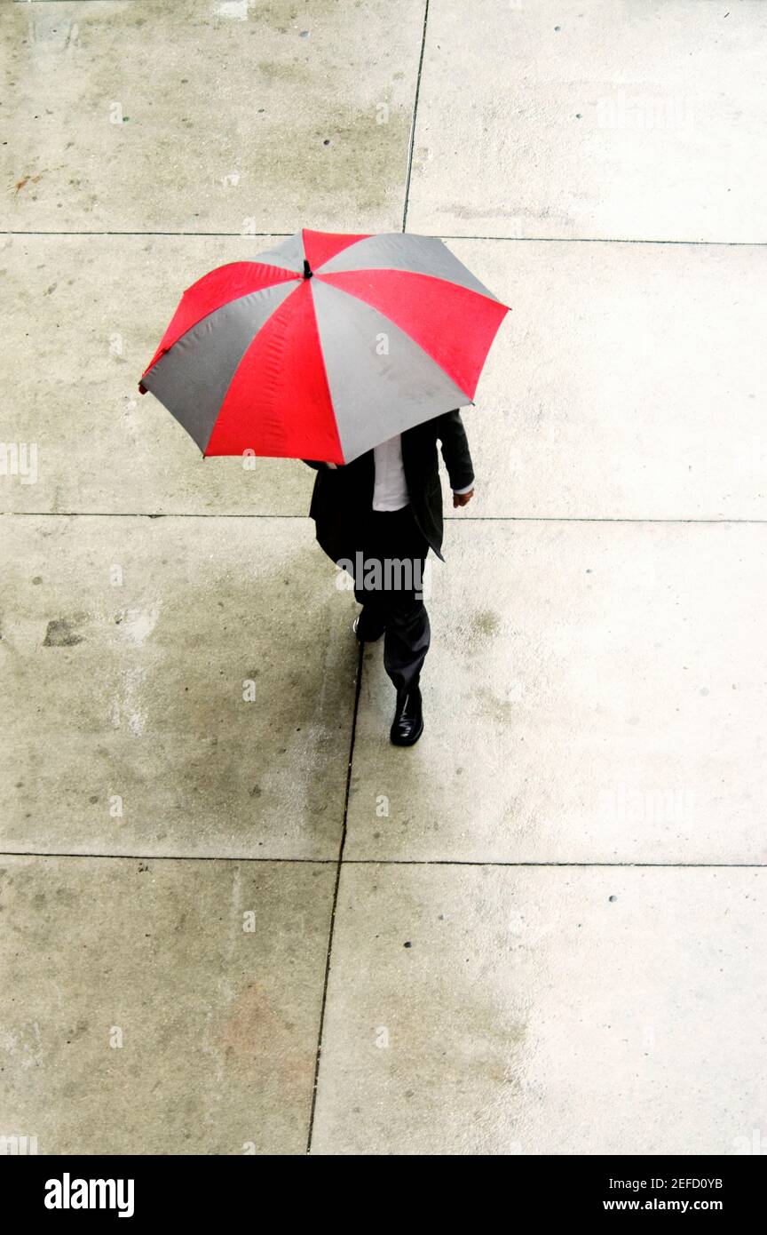 Vista ad alto angolo di un uomo d'affari che cammina con un ombrello Foto Stock
