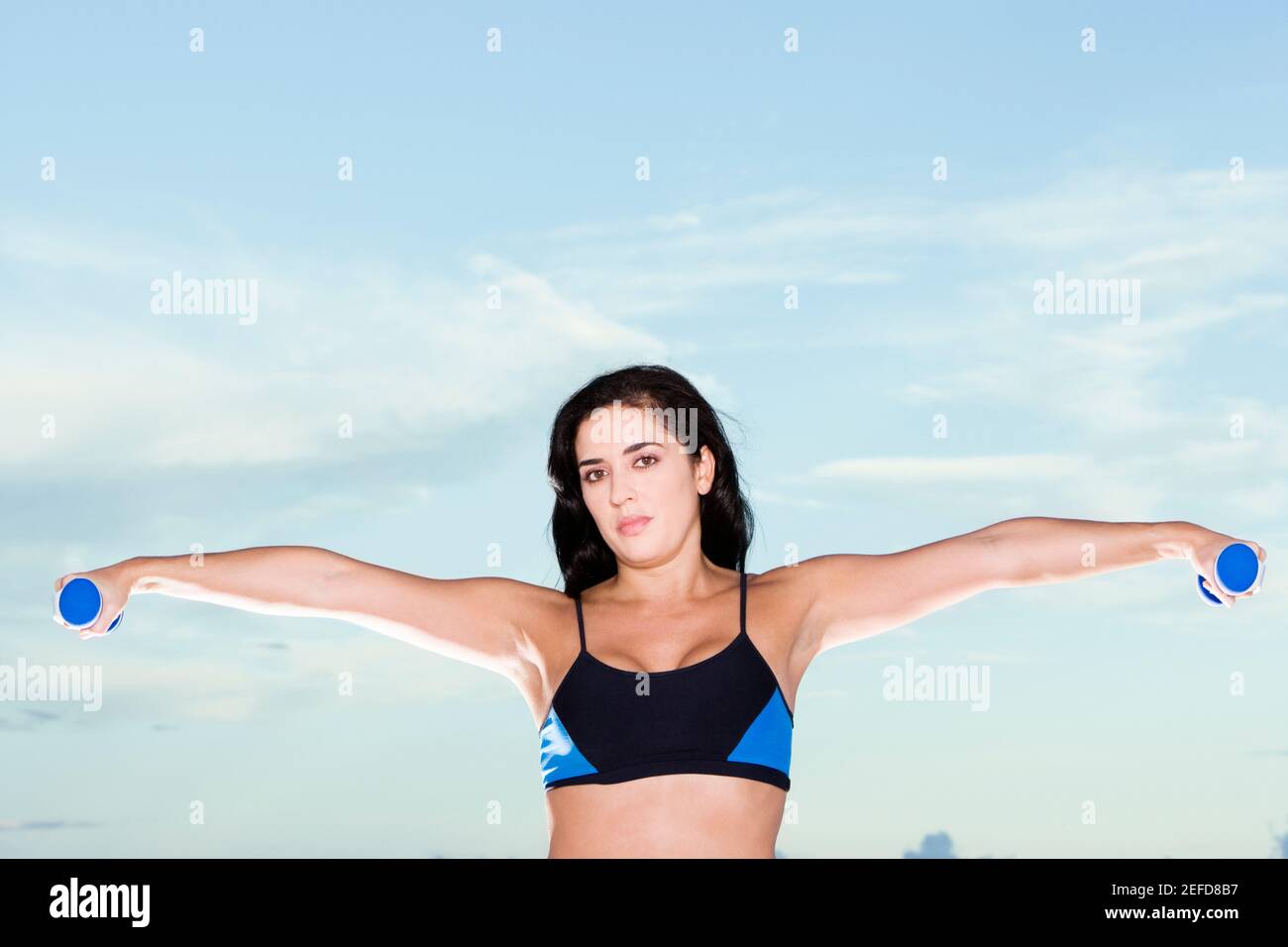 Ritratto di una donna mid adulta che si esercita con manubri Foto Stock