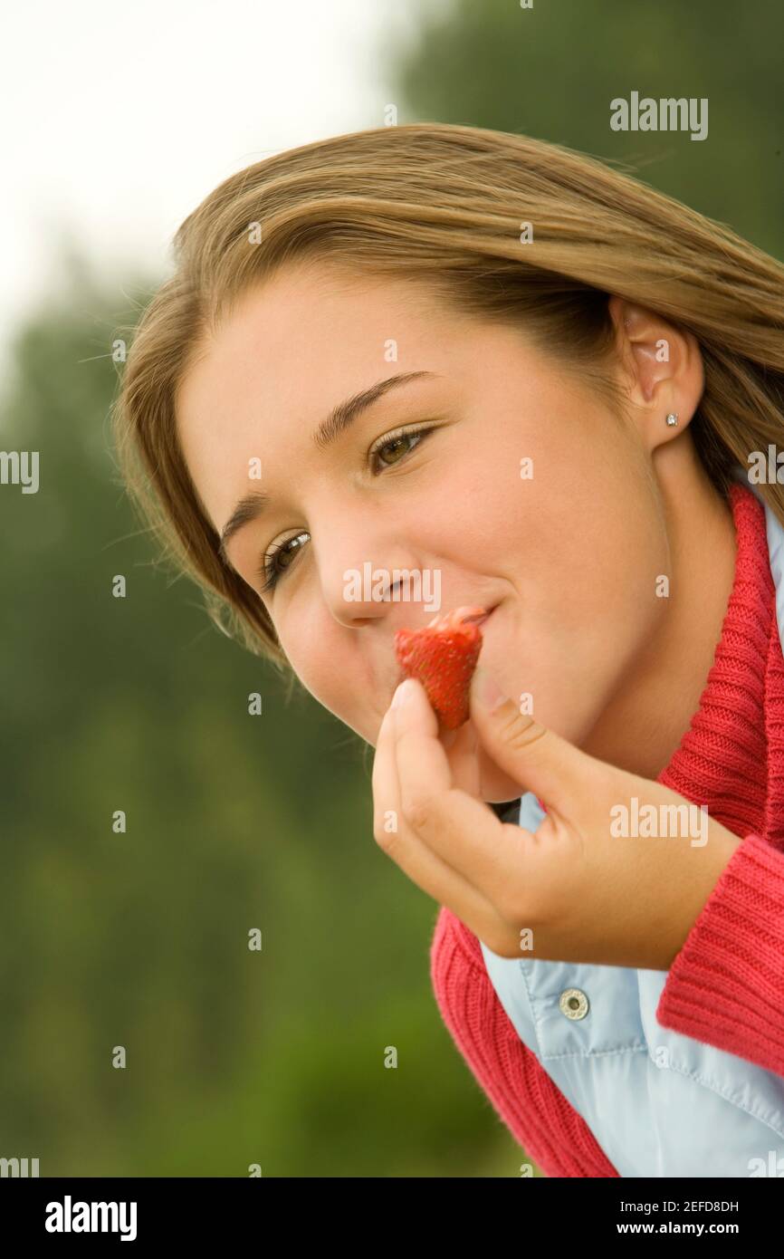 Primo piano di una ragazza adolescente che mangia una fragola Foto Stock