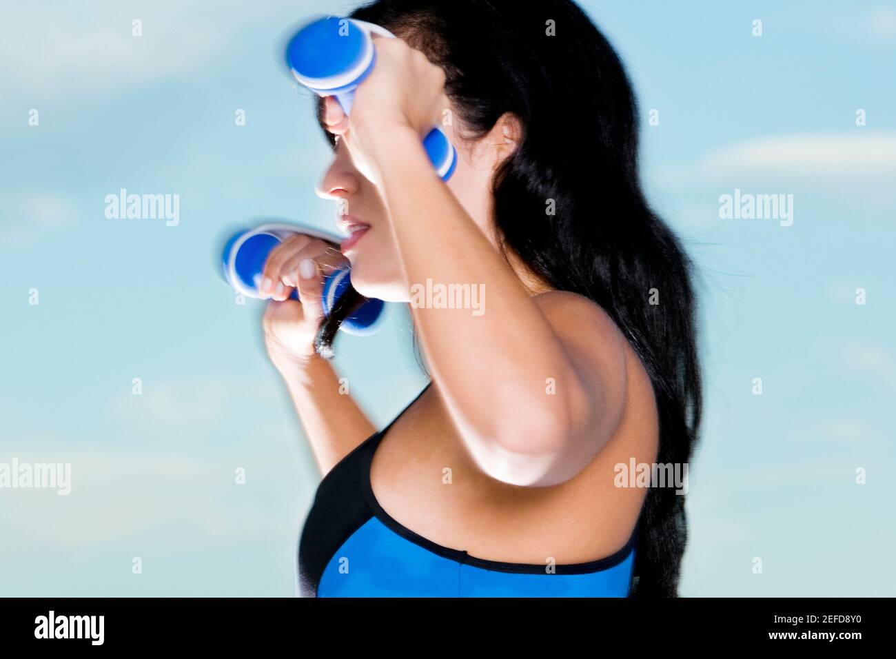 Profilo laterale di una donna mid adulta che si esercita con manubri Foto Stock