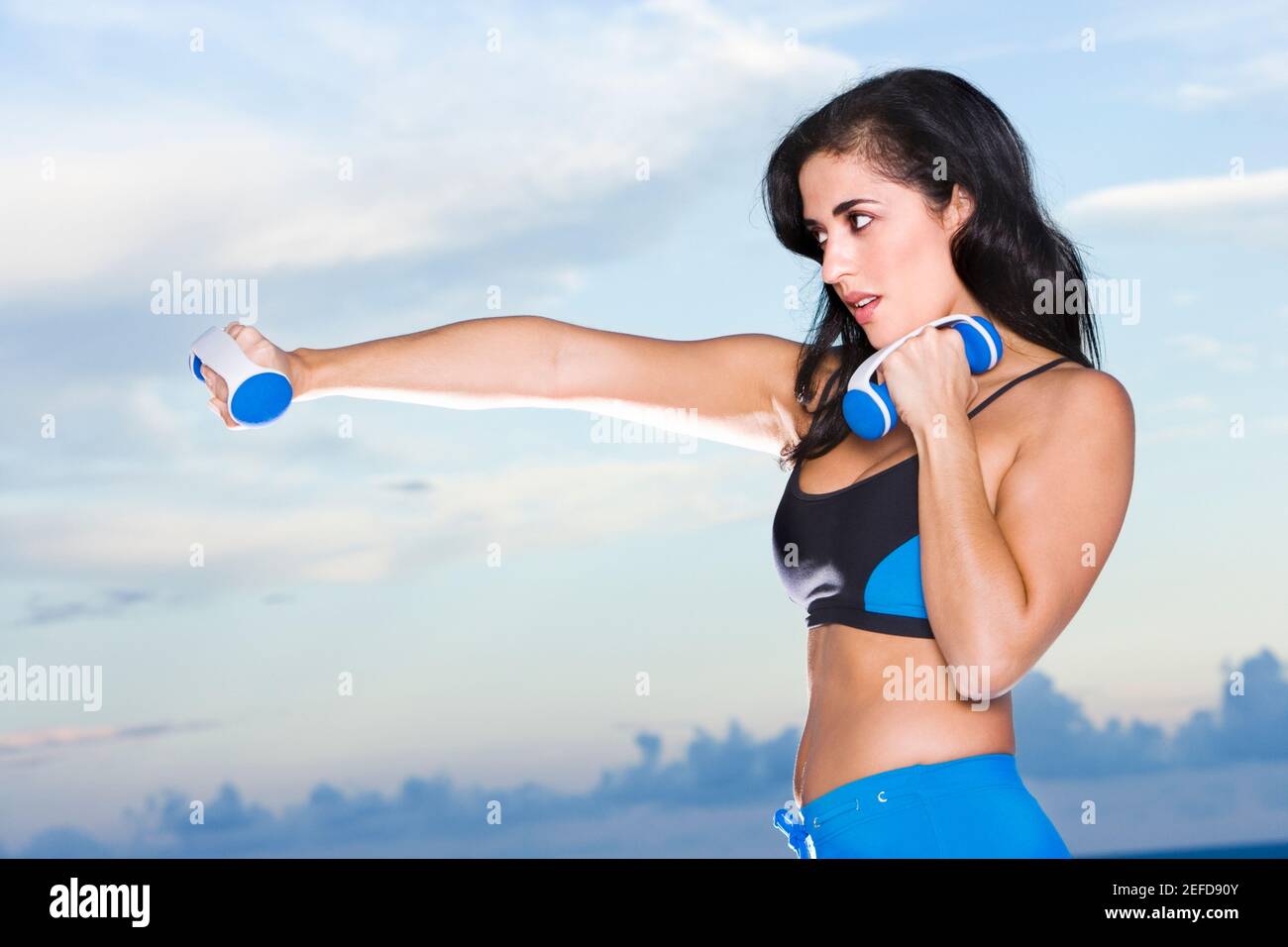 Profilo laterale di una donna mid adulta che si esercita con manubri Foto Stock