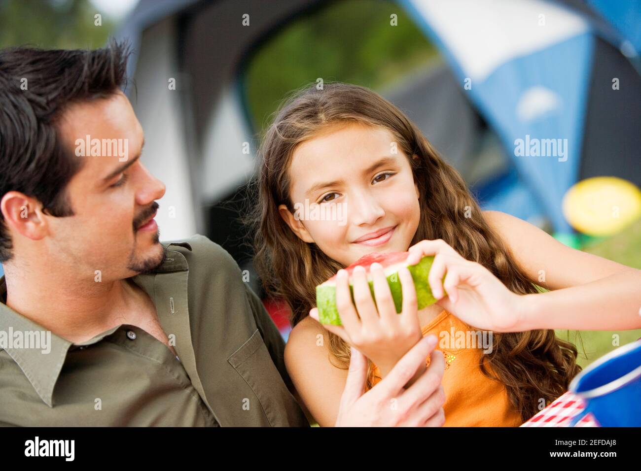 Ritratto di una ragazza che tiene un cocomero con il padre guardandola Foto Stock
