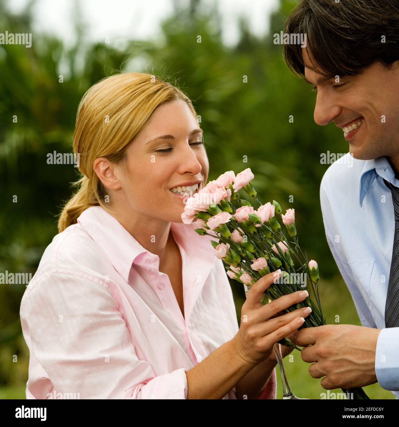 Primo piano di un uomo d'affari che tiene un mazzo di fiori con una donna d'affari li odorava Foto Stock