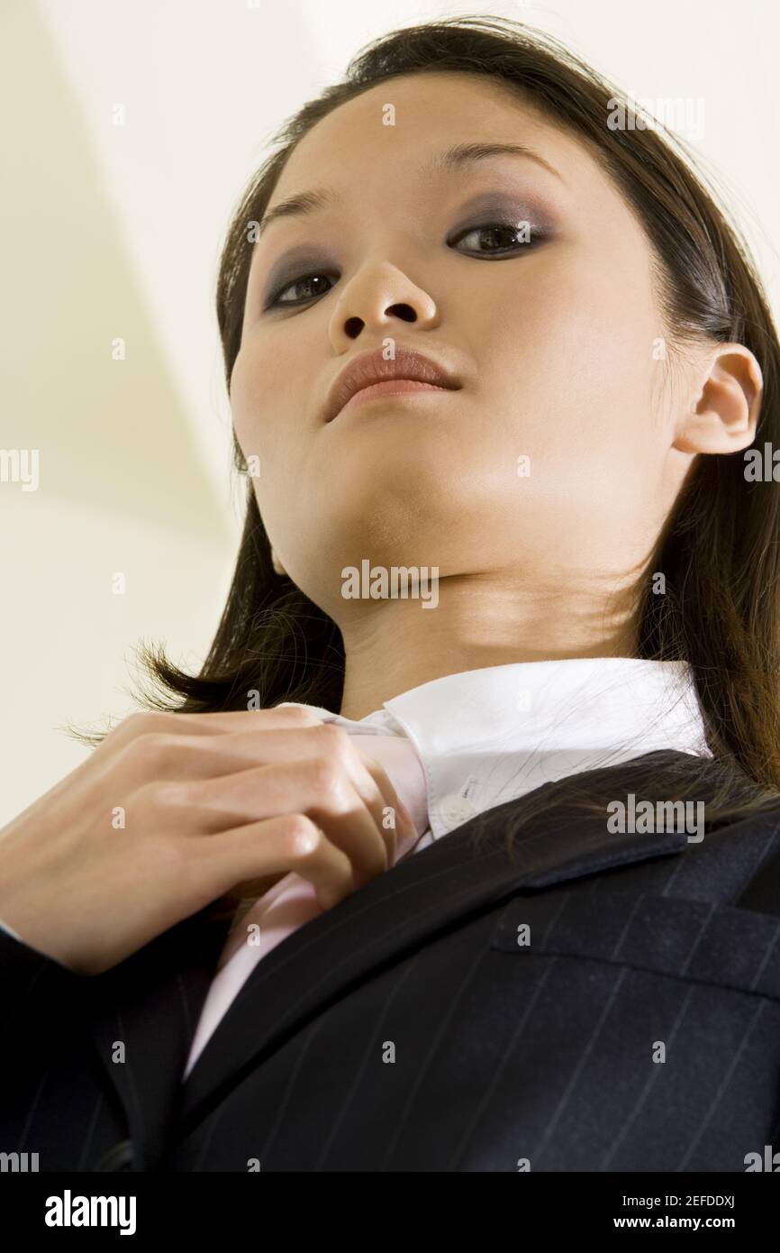 Vista ad angolo basso di una donna d'affari che regola la sua cravatta Foto Stock