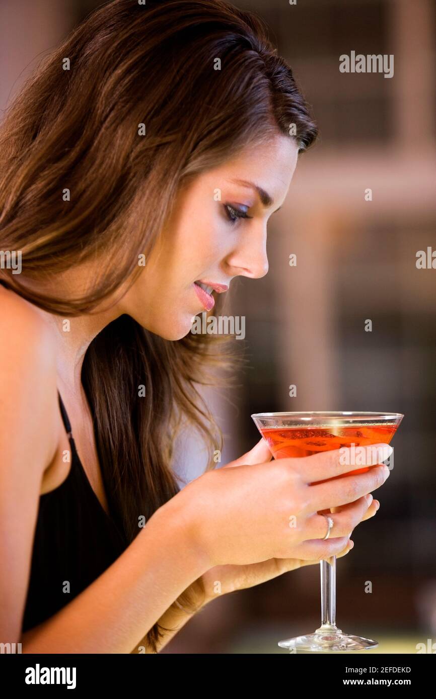 Profilo laterale di una giovane donna con in mano un bicchiere di martini Foto Stock