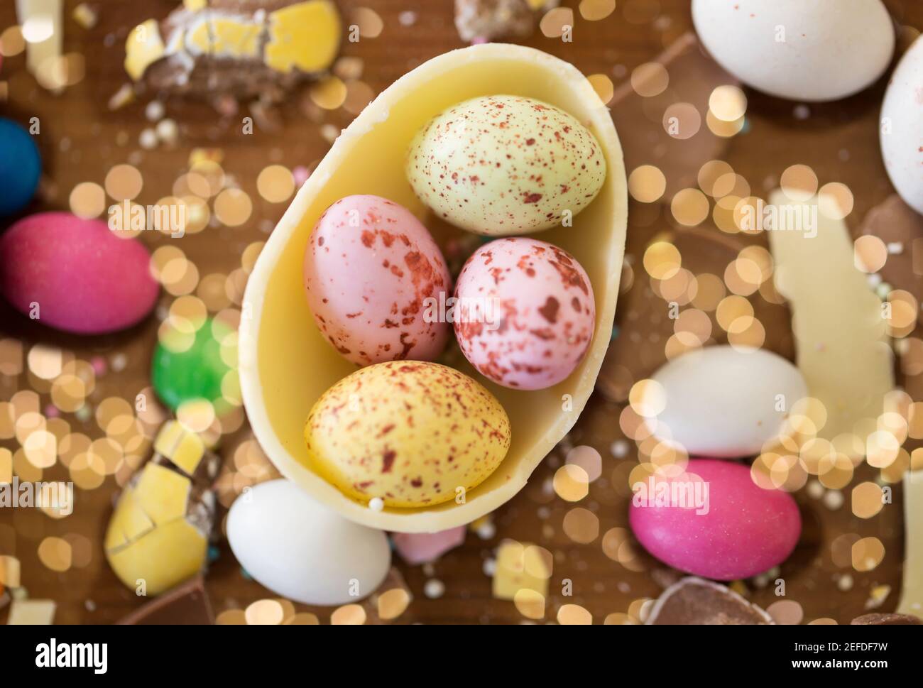 Uovo di cioccolato e caramelle gocce sul tavolo di legno Foto Stock