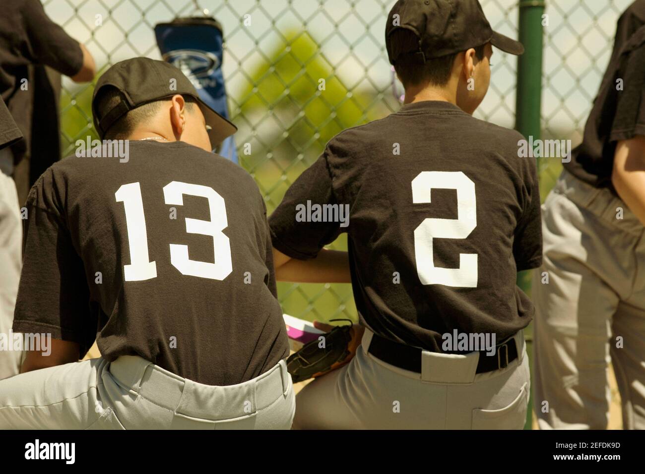 Vista posteriore di due giocatori di baseball seduti su una panchina Foto Stock