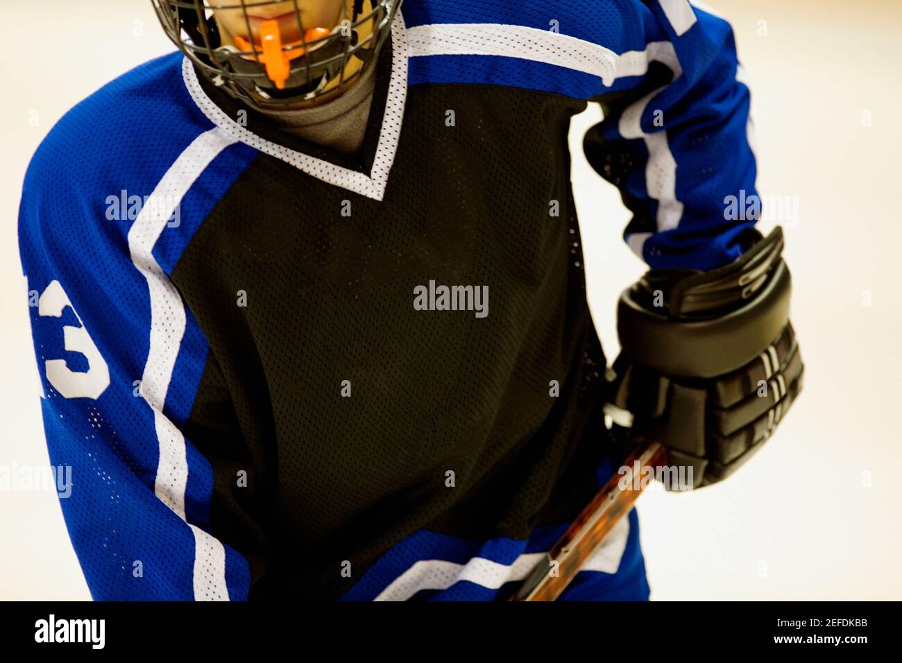 Vista in sezione intermedia di un giocatore di hockey su ghiaccio che tiene un bastone per hockey su ghiaccio Foto Stock