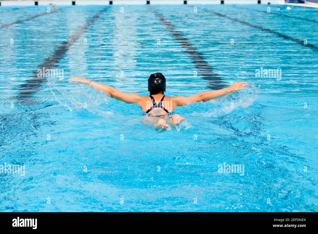 Vista posteriore di una giovane donna che nuota in una nuotata piscina Foto Stock