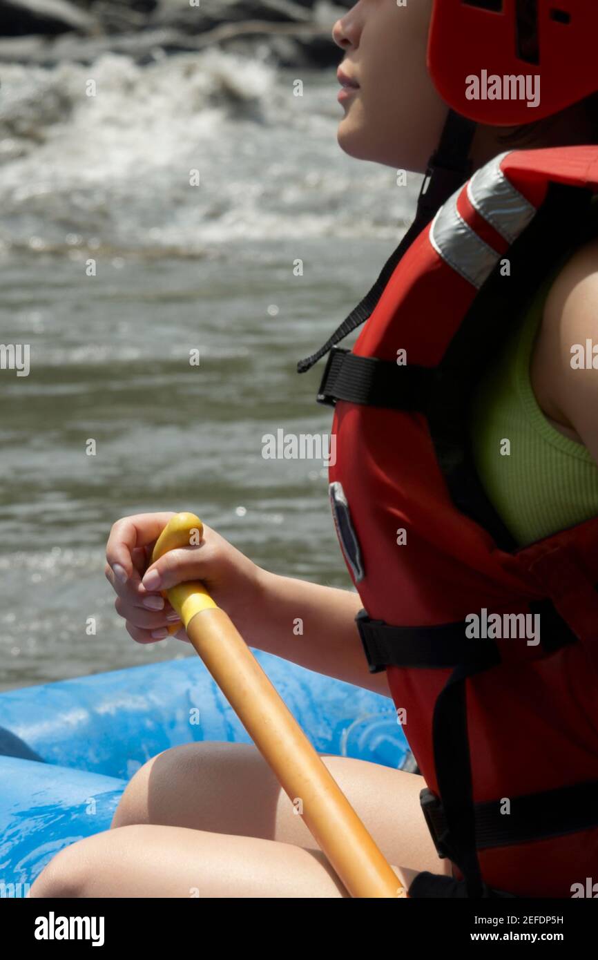 Profilo laterale di una giovane donna che rafting in un fiume Foto Stock