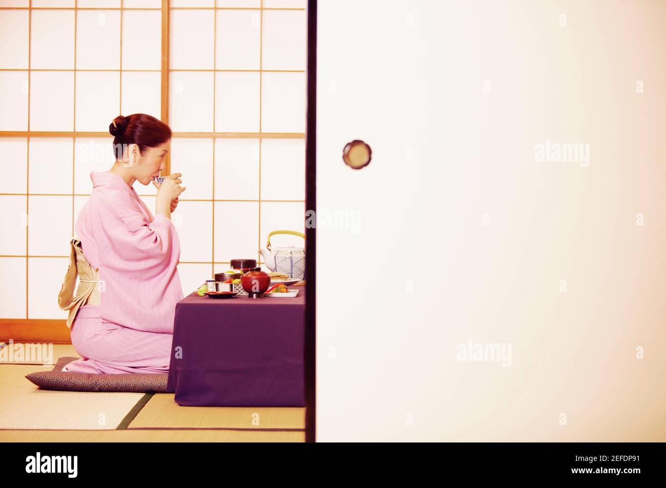 Profilo laterale di una donna matura che indossa un Kimono e. bere da una tazza Foto Stock