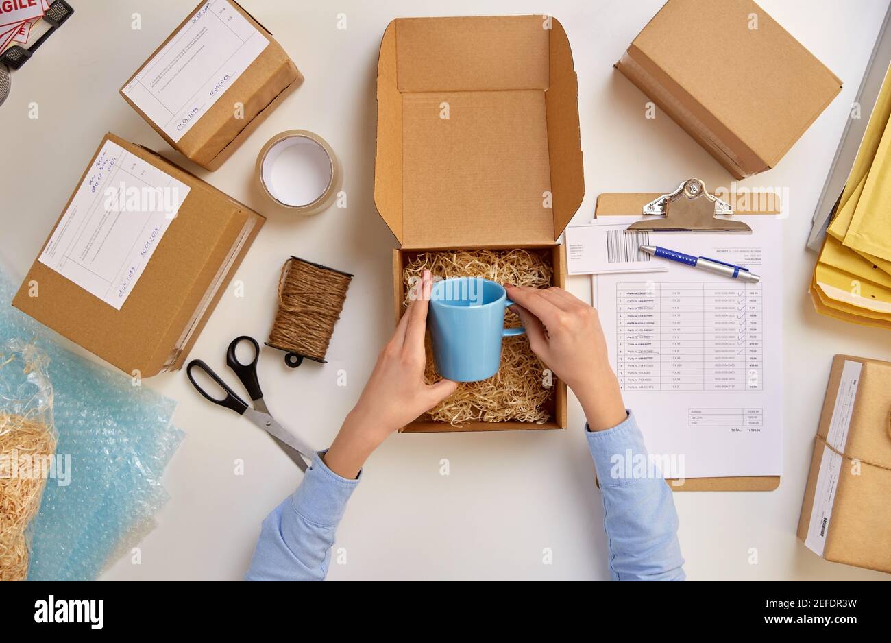 consegna la tazza di imballaggio alla scatola del pacco presso l'ufficio postale Foto Stock
