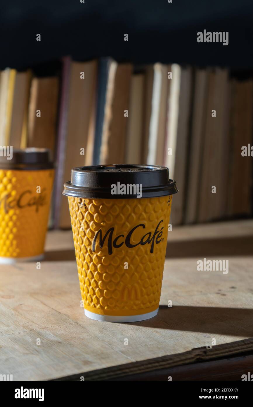Ucraina, Kiev - 17 febbraio 2021: Bicchiere giallo di caffè da McDonald's. Bicchiere di carta McCafe. Tazza di caffè offee sul tavolo con ombre. Menu in fast food Foto Stock