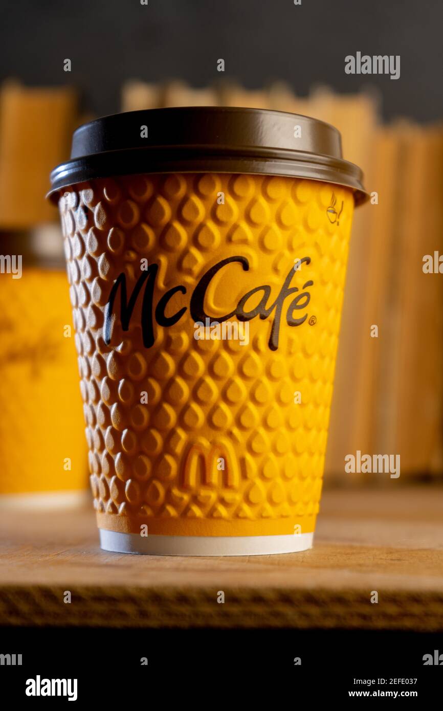Ucraina, Kiev - 17 febbraio 2021: Bicchiere giallo di caffè da McDonald's. Bicchiere di carta McCafe. Tazza di caffè offee sul tavolo con ombre. Menu in fast food Foto Stock