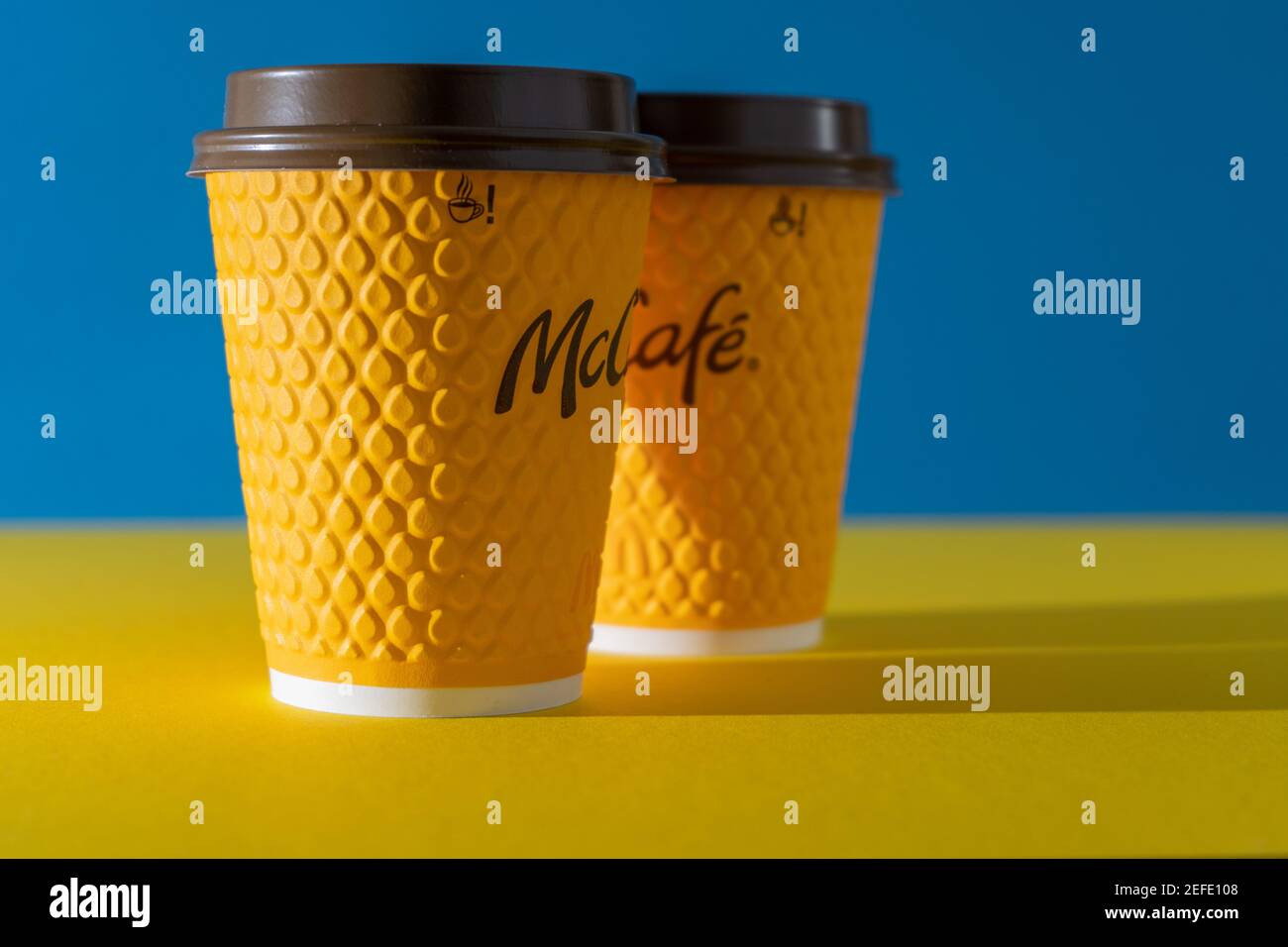 Ucraina, Kiev - 17 febbraio 2021: Bicchiere giallo di caffè da McDonald's. Bicchiere di carta McCafe. Tazza di caffè offee sul tavolo con ombre. Menu in fast food Foto Stock