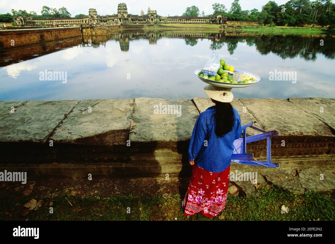 Vista posteriore di un venditore femminile che porta frutta di lime sulla sua testa, Angkor Wat, Angkor, Siem Reap, Cambogia Foto Stock