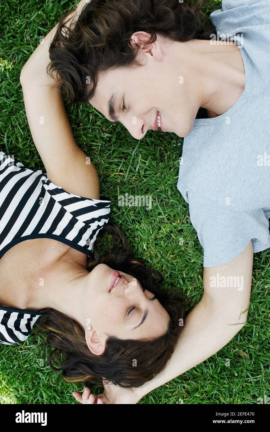 Vista ad alto angolo di una giovane coppia sdraiata sul erba in un parco Foto Stock