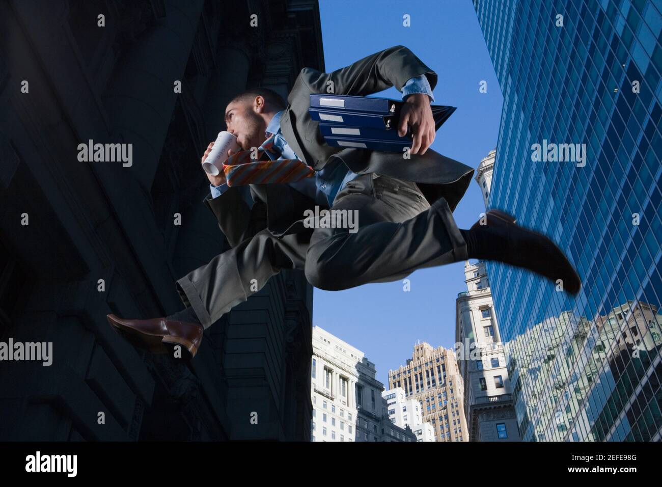 Vista ad angolo basso di un uomo d'affari che salta in aria media e. bere Foto Stock