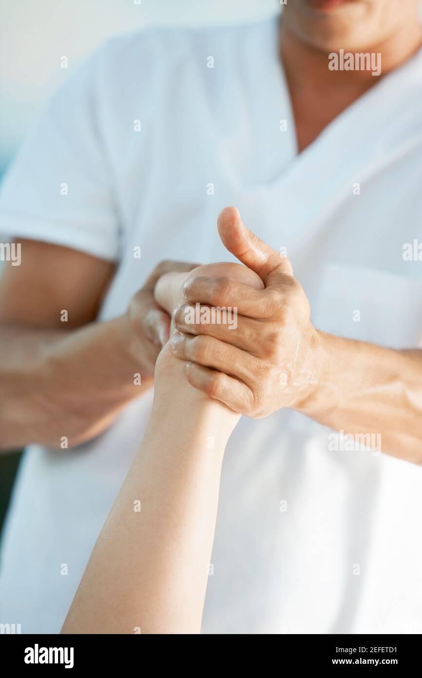 Vista in sezione intermedia di un massaggiatore che offre massaggio ai piedi a una donna Foto Stock
