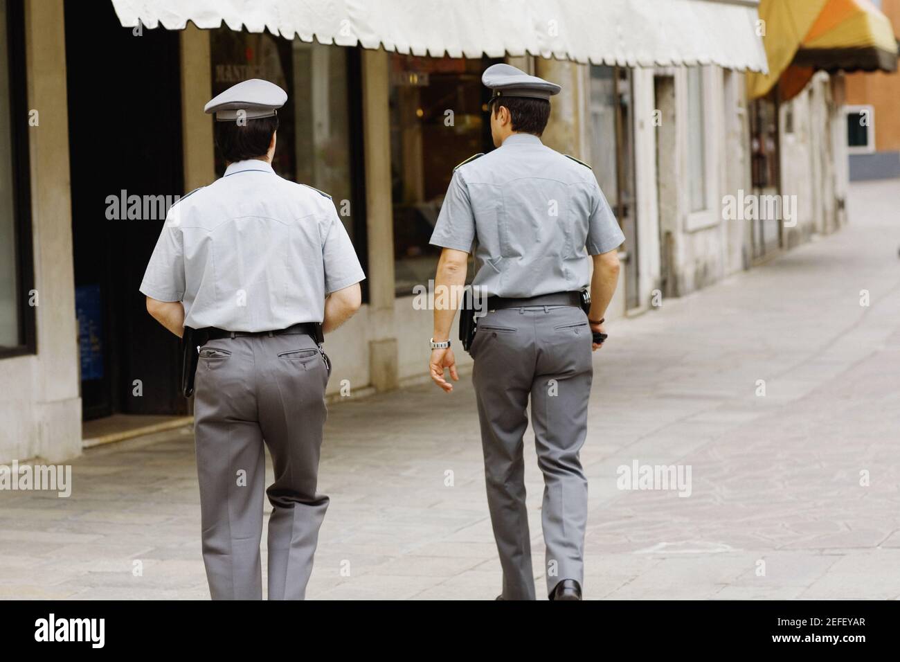 Vista posteriore di due poliziotti che camminano verso un edificio, Venezia, Veneto, Italia Foto Stock