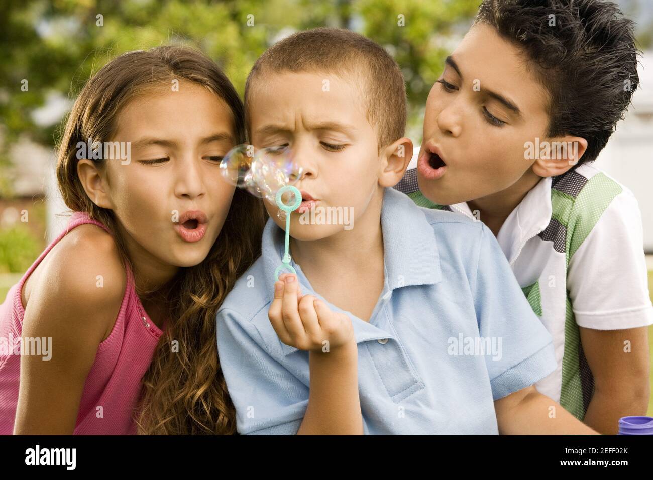 Primo piano di un ragazzo che soffia bolle con una ragazza e. un ragazzo accanto a lui Foto Stock