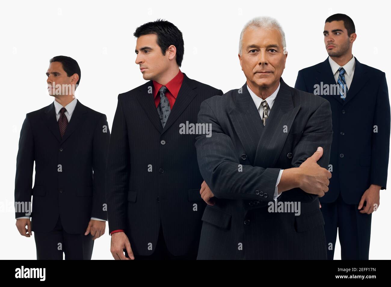 Uomo d'affari che guarda serio con tre uomini d'affari in piedi dietro di lui e. guardando via Foto Stock