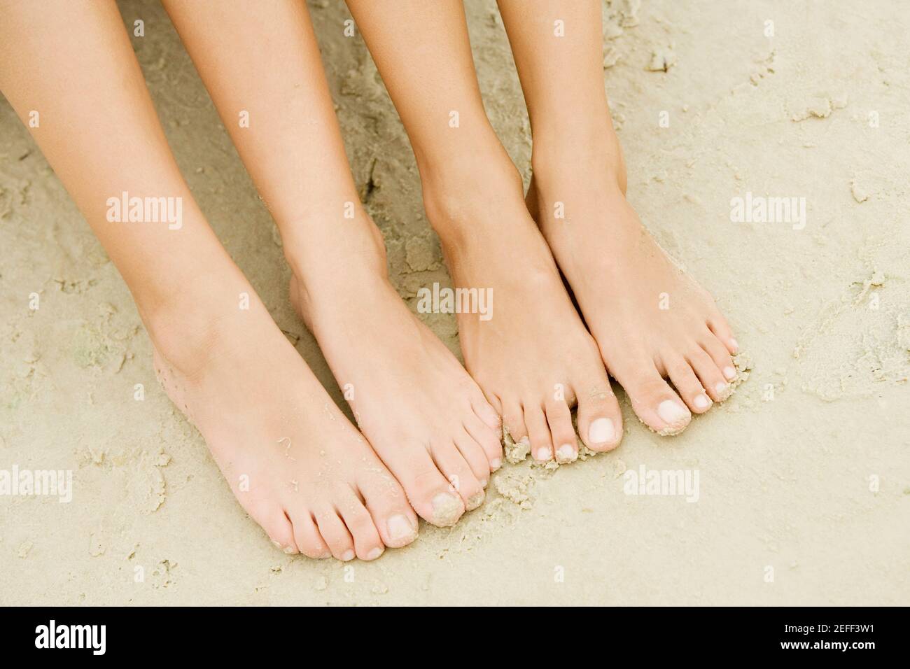 Vista ad angolo alto dei piedi di due persone sabbia Foto Stock