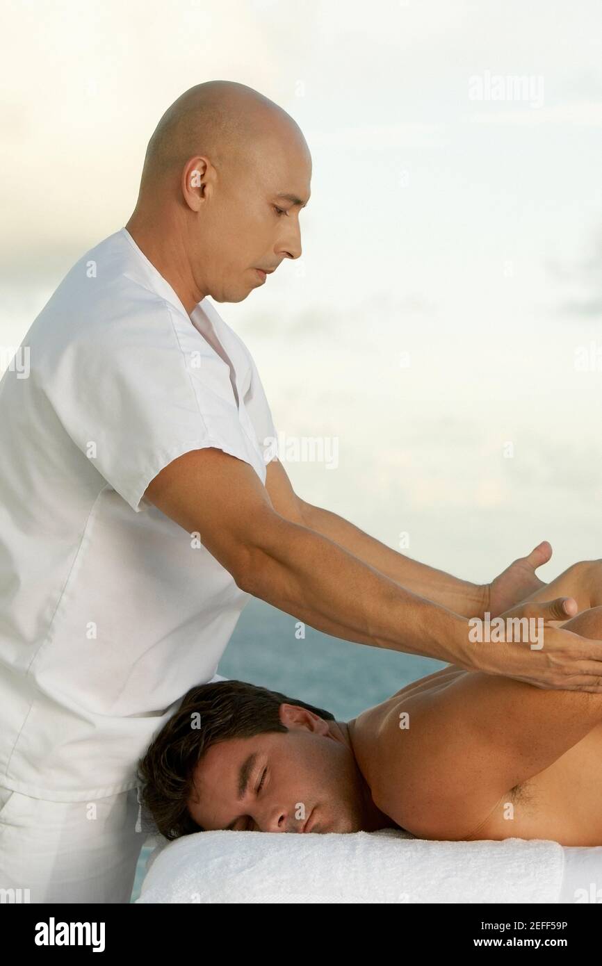 Profilo laterale di un uomo maturo che dà un adulto medio uomo un massaggio alla schiena Foto Stock