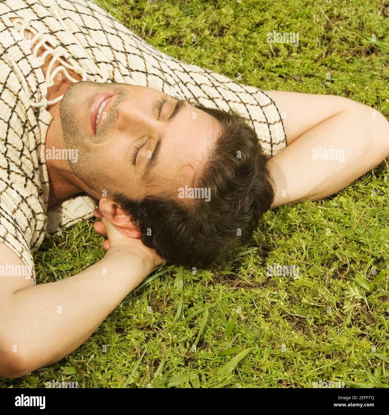 Vista ad alto angolo di un uomo medio adulto che dorme sopra l'erba Foto Stock