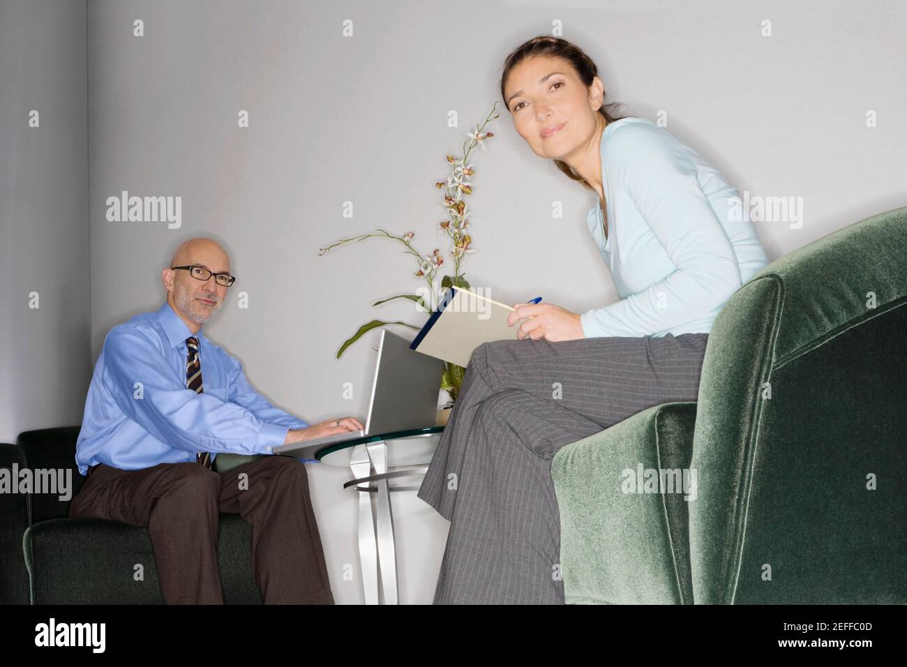 Uomo d'affari che usa un computer portatile con una donna d'affari seduto di fronte di lui Foto Stock