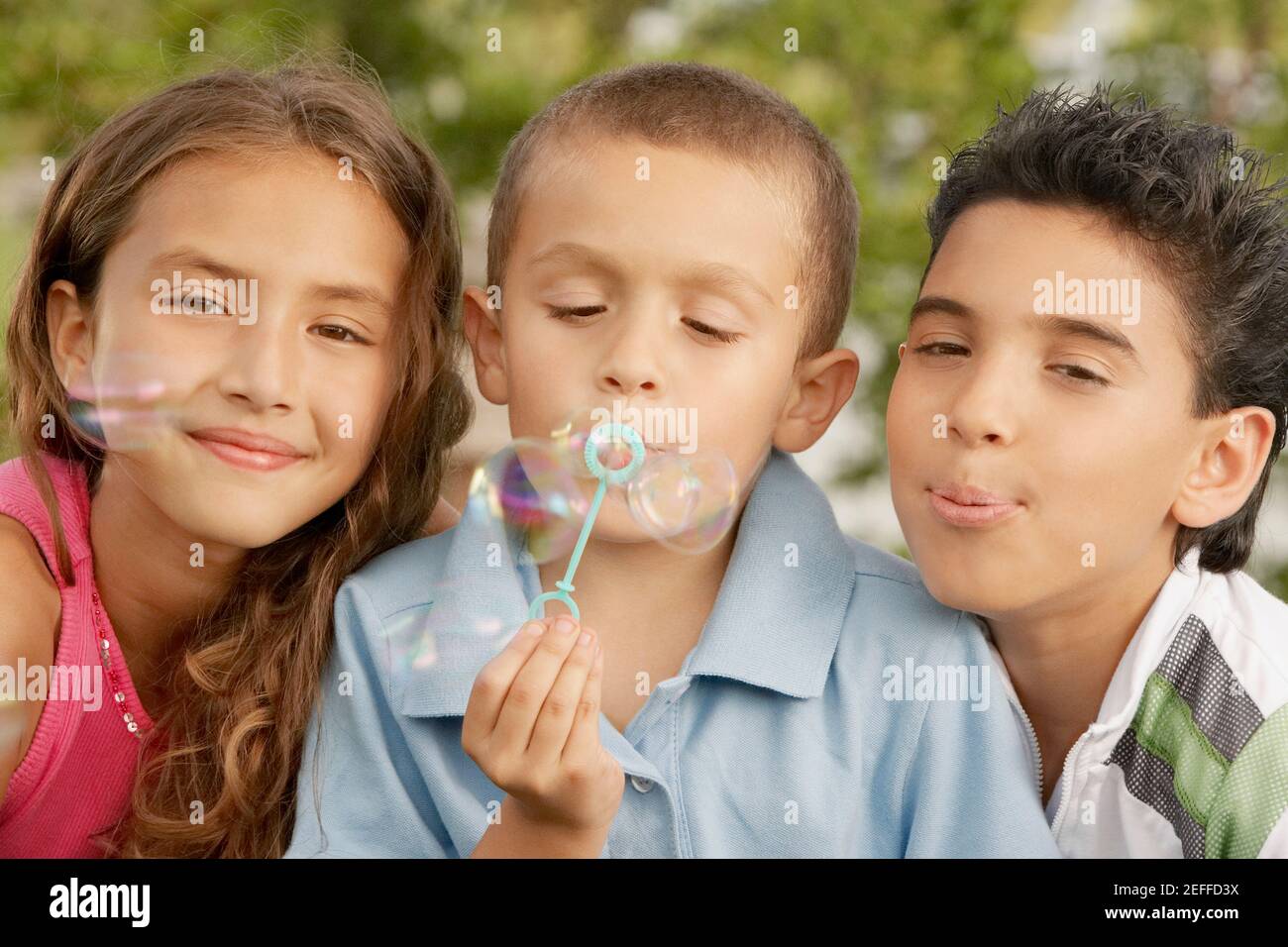 Ritratto di un ragazzo che soffia bolle con la sorella e. fratello Foto Stock