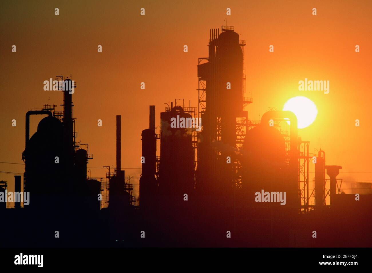 Impianti chimici di raffineria e smokestacks in silhouette Foto Stock