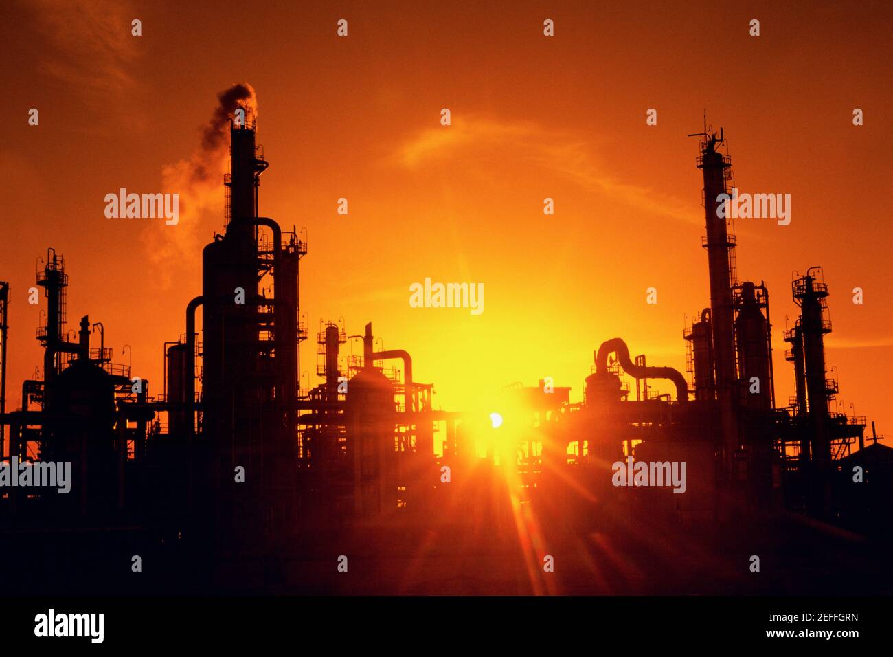 Impianti chimici di raffineria e smokestacks in silhouette Foto Stock