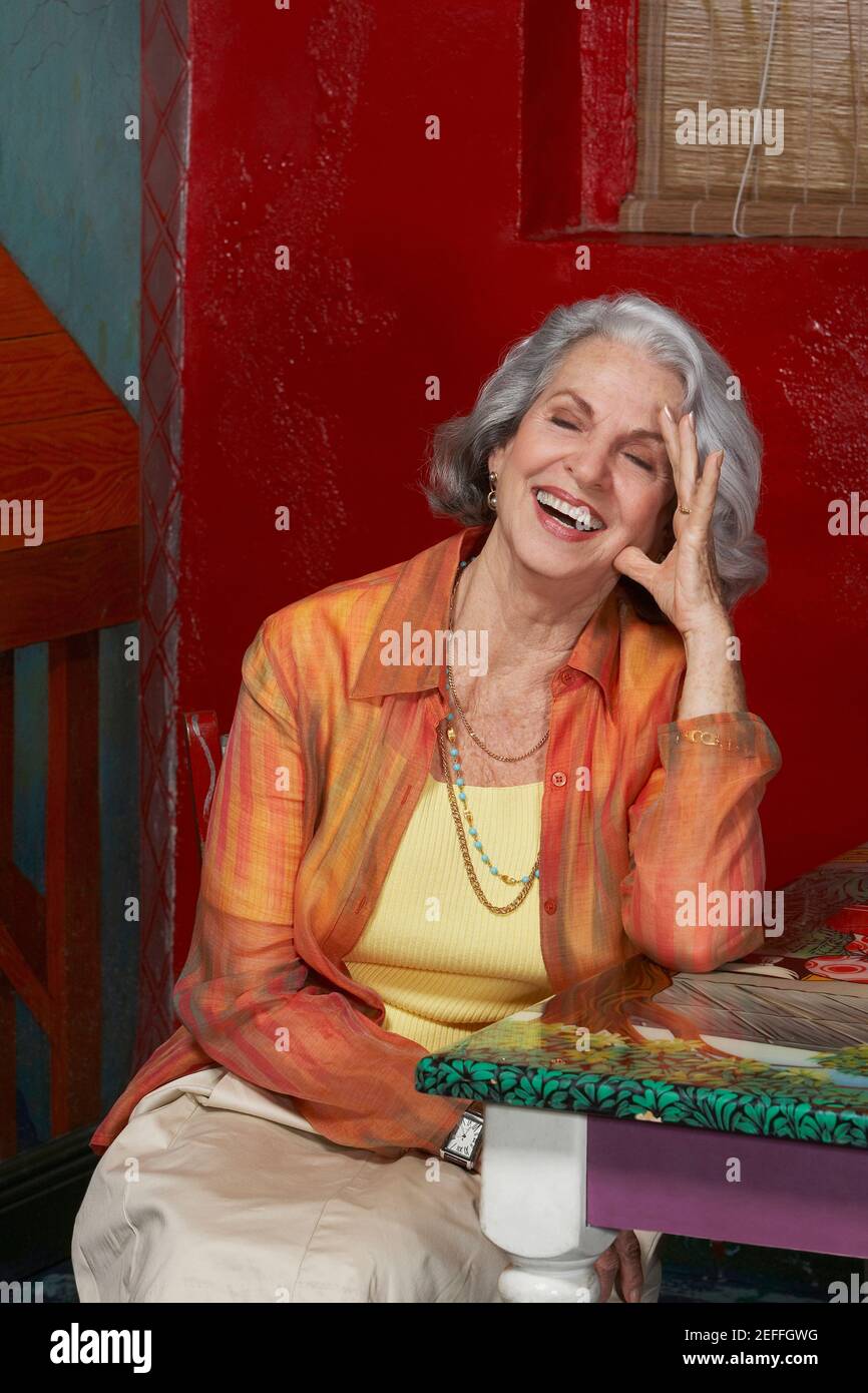 Senior donna seduta in un ristorante e ridere Foto Stock