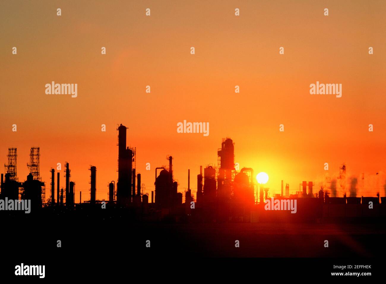 Impianti chimici di raffineria e smokestacks in silhouette Foto Stock