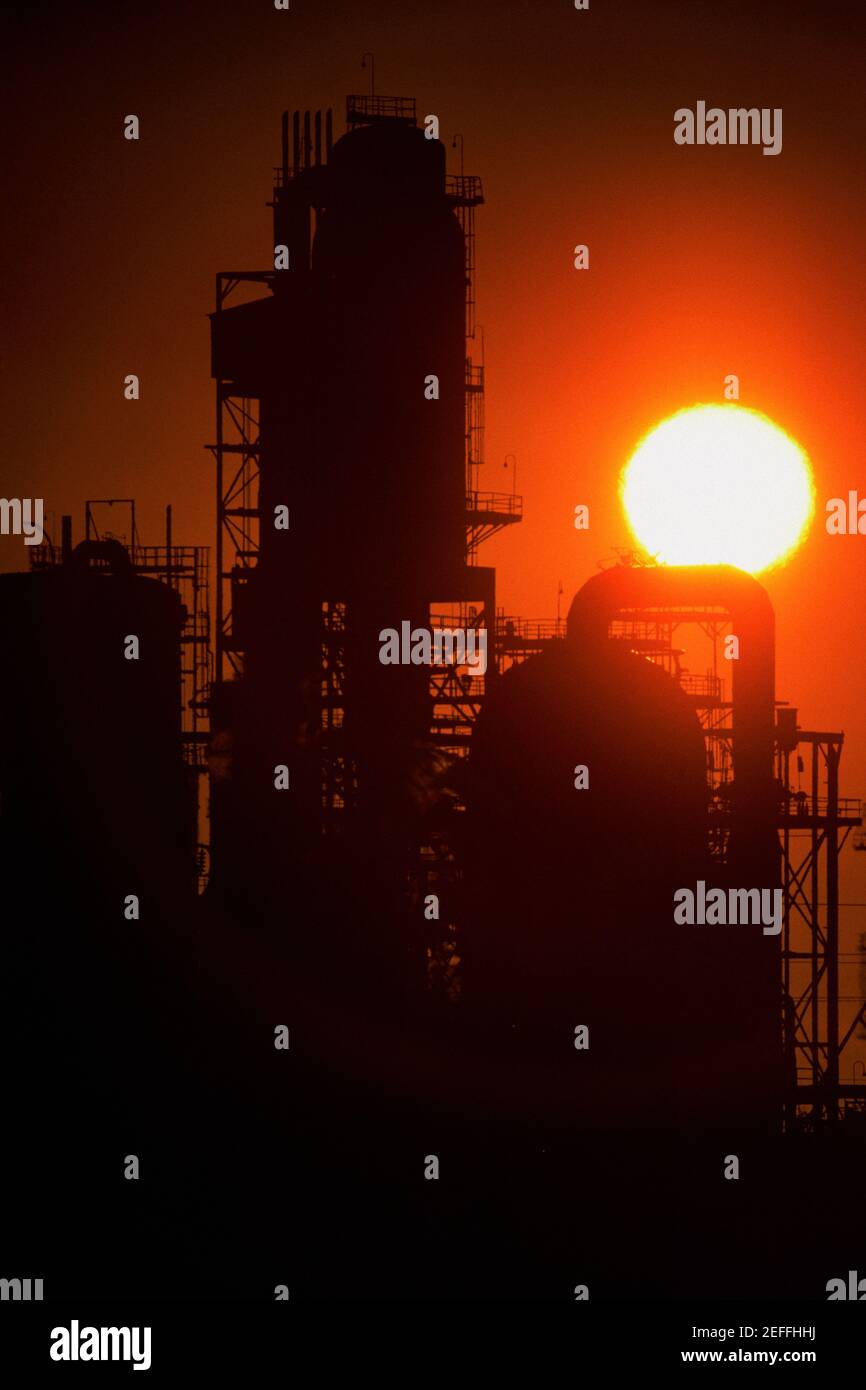 Impianti chimici di raffineria e smokestacks in silhouette Foto Stock