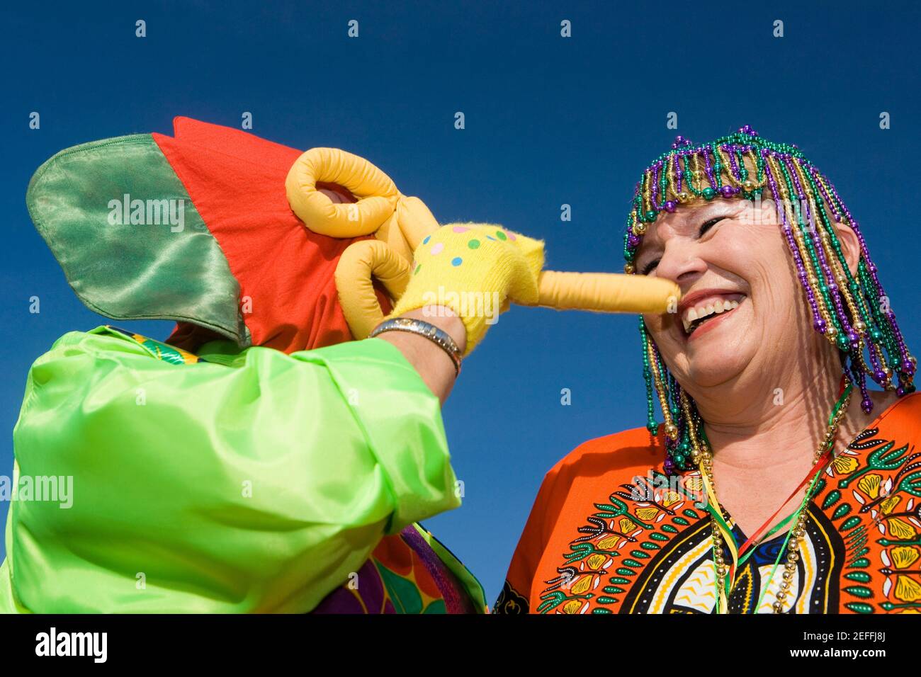 Vista ad angolo basso di una donna anziana che indossa un headdress con perline e guardando un'altra donna Foto Stock