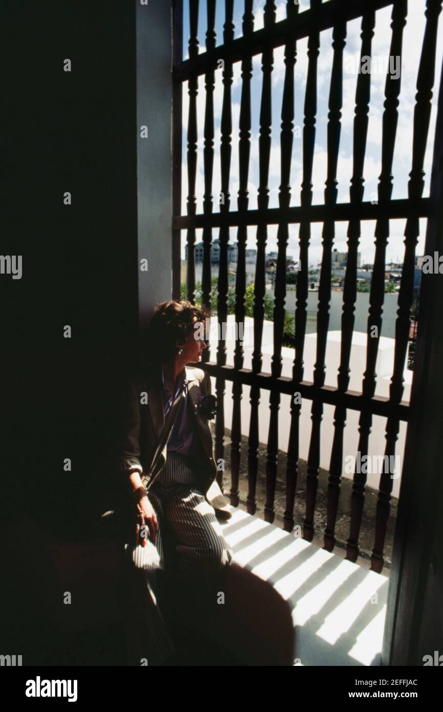 Una donna solita si affaccia attraverso un cancello dalla silhouette, Old San Juan, Puerto Rico Foto Stock