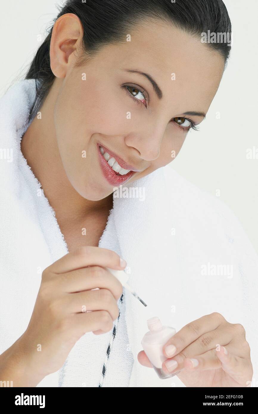 Ritratto di una giovane donna che tiene smalto unghie e sorridente Foto Stock