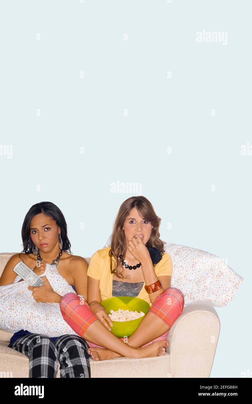 Due giovani donne seduta su un divano e guardare la televisione Foto Stock