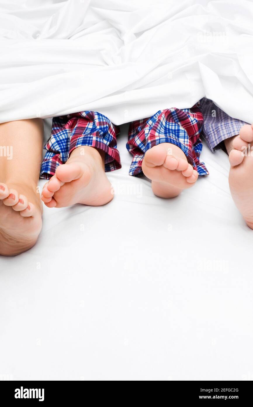 Primo piano di un coupleÅ½s piedi con il loro bambino sul letto Foto Stock