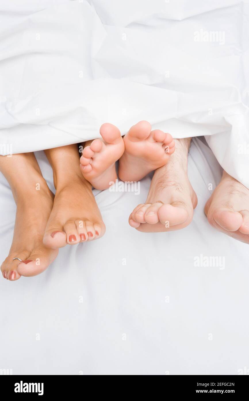 Vista ad alto angolo di un coupleÅ½s piedi con il bambino sul letto Foto Stock
